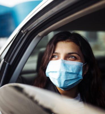 A,Woman,Wearing,A,Medical,Sterile,Mask,In,A,Taxi